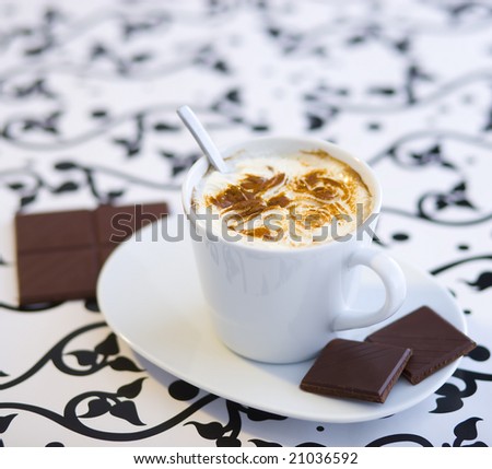 Hot coffee with home made cream and chocolate on the table with black - white cloth