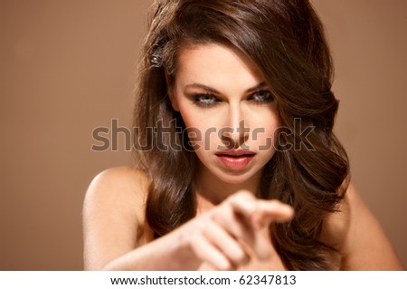Portrait of beautiful woman pointing at you isolated on beige