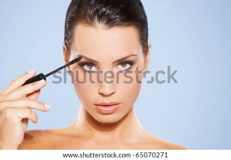 stock photo : Portrait of beautiful woman she is doing makeup, isolated on blue background