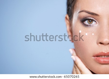 Face part of beautiful woman with cream on face on natural background