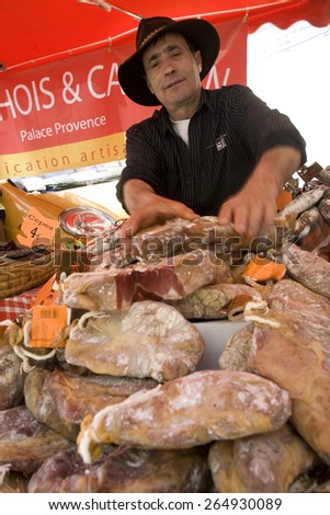 man selling traditional artisan meat on a market stall,Languedoc, southern France.taken 15/09/2008