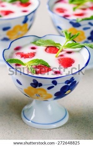 Strawberries desert with cream served on ice cream bowls over table top