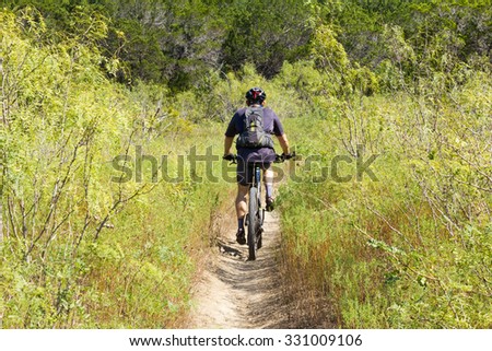 AUSTIN, TEXAS: SEPTEMBER 13 2015: A lone mountain biker rides away on a trail at Stephenson Nature Preserve and Outdoor Education Center