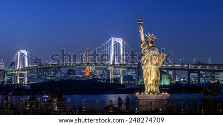Statue of Liberty and Rainbow bridge, located at Odaiba Tokyo, with Tokyo skyline in  background at twilight