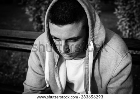 young boy in sweater sitting on bench, black and white photo