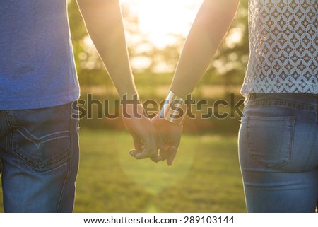 young couple holding hands in sunset