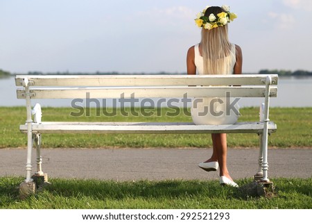 young pretty woman sitting on bench with her back, rosary beads on head
