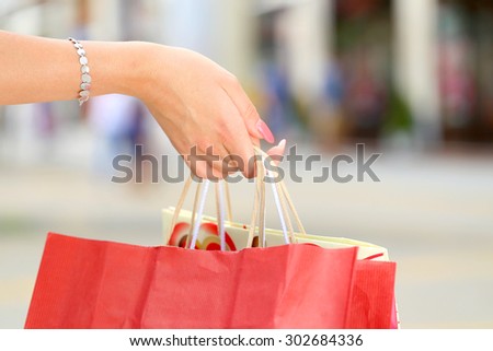 woman hand holding shopping bags on street