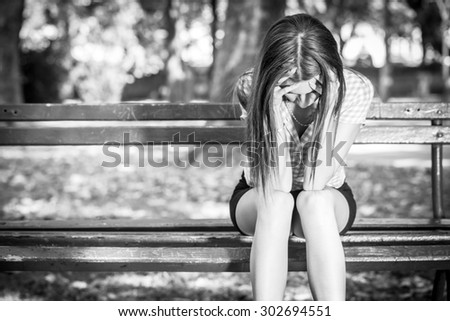 sad woman sitting on bench in a park, black and white photography