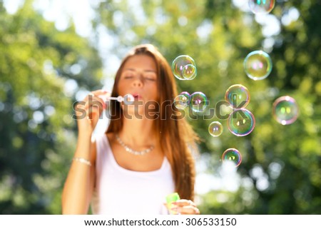 young girl inflating  soap bubbles in park