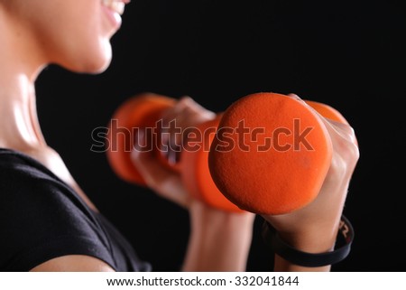 close up side view of fitness woman lifting dumbbells isolated on black background