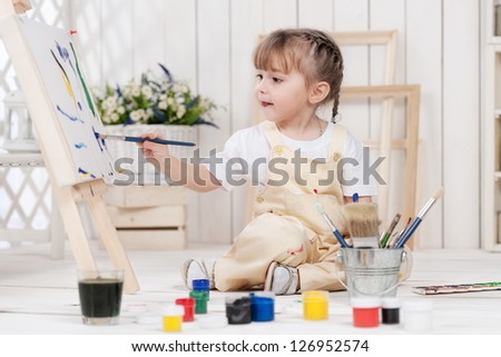 Little girl artist paints in his studio