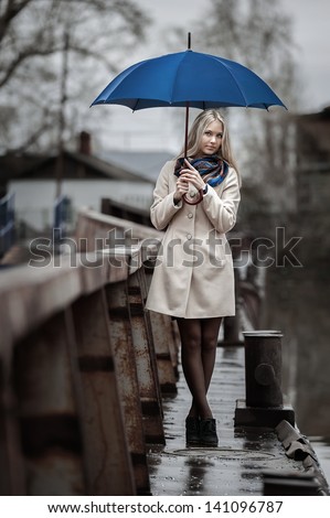 Young girl with an umbrella on a bridge in the rain