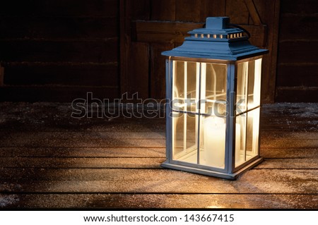 Garden lamp with lighted candles in the winter snowy night