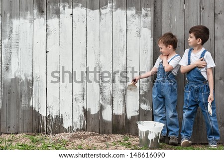 Boys with brushes and paint at an old wall