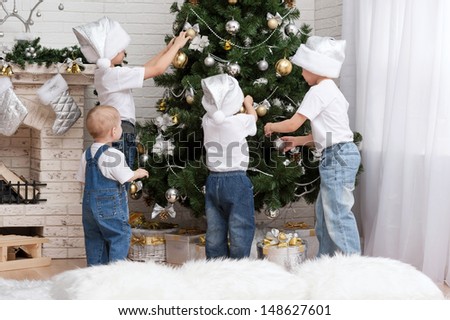 Four young children decorate the Christmas tree with beautiful toys