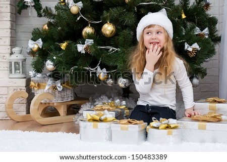 Happy little girl by the fireplace under the Christmas tree