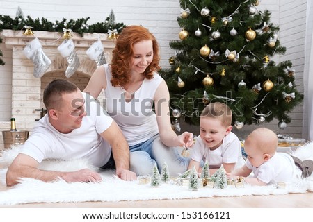Happy young family at the Christmas tree with a fireplace