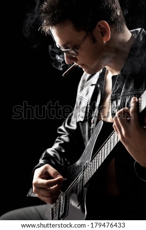 Young man playing guitar on a black background