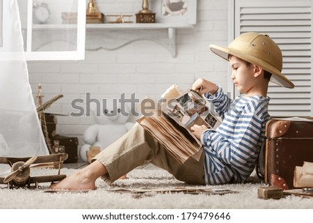 Boy in the image traveler studying his book of travel and adventure in her room