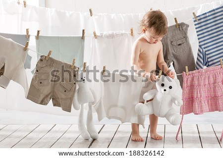 Little girl hangs laundry or toys in the laundry