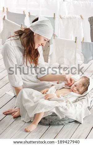 Mother with sleeping in a basin with baby clothes in the laundry