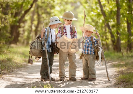 Boys travelers with backpacks studying the route map in a sunny summer day
