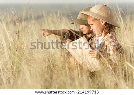 Small tourists looking into the distance through the thick grass steppe in summer sunny day