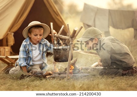 Two little boy are heated in a fire and cook out on a summer evening
