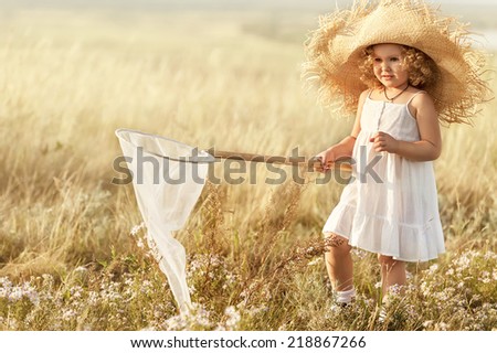 Little girl with butterfly net catching butterflies in the meadow sunny summer day