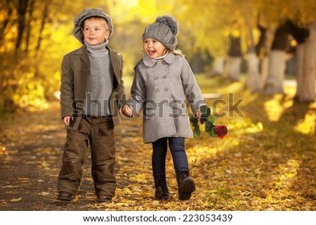 Boy and girl walk in autumn park on a warm sunny day, soft focus