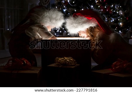 Children in Christmas night under the tree by the fireplace with a magical gift