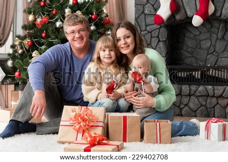 Portrait of a young family with children at home New Year\'s Eve by the fireplace and near the Christmas tree