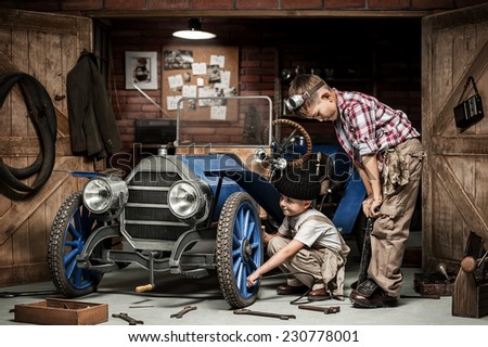 Two boys Mechanical inflated tire on the retro car in the garage