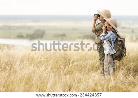 Two boys, a tourist looking through binoculars into the distance on the precipice summer day