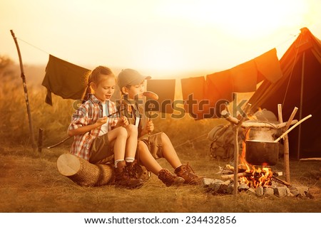 Two children - boy and girl are heated in a fire and cook out on a summer evening