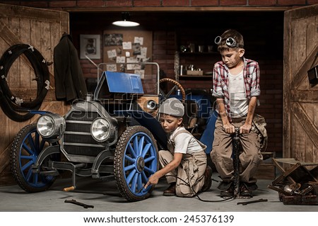 Two boys Mechanical inflated tire in retro car in the garage