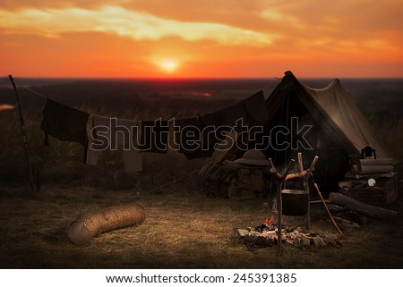 Tent, campfire - tourist destination summer evening on a hilltop at sunset