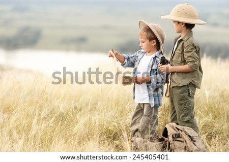 Two boys look-tourist route on the map on the precipice of a summer day