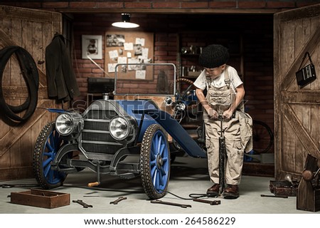 Little boy Mechanical pumps wheel retro car in the garage