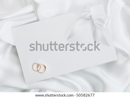 stock photo The wedding invitation with wedding rings on a white 