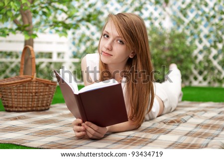 Young girl reads a book in the garden