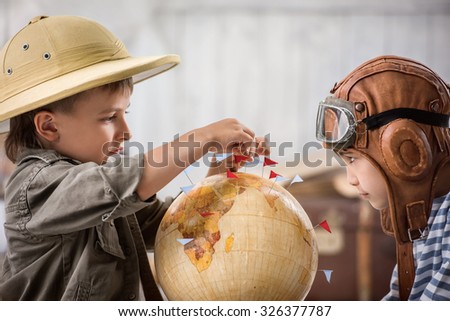 Two boys in the form of pilot and tourists planning on a globe of their travel route