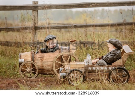 Two boys, riders compete against each other on homemade wooden car on rural road. Retouch for retro