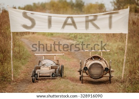 Two homemade wooden car racing at the start on the rural outskirts. Retouch for retro