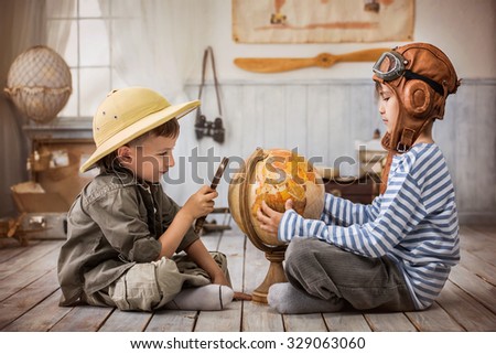 Two boys in the form of pilot and tourists planning on a globe of their travel route