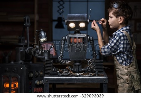 Young boy mechanic repairing the robot in the workshop at night