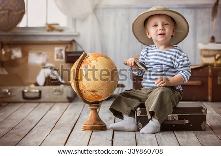 Little boy in the form of tourists planning on a globe of their travel route