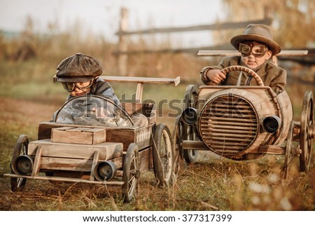 Two boys, riders compete against each other on homemade wooden car on rural road. Retouch for retro