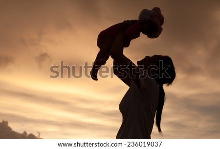 Daughter in her mother\'s arms silhouetted at cloud of bad weather at Thailand. Mother\'s & baby is motion-blurred.